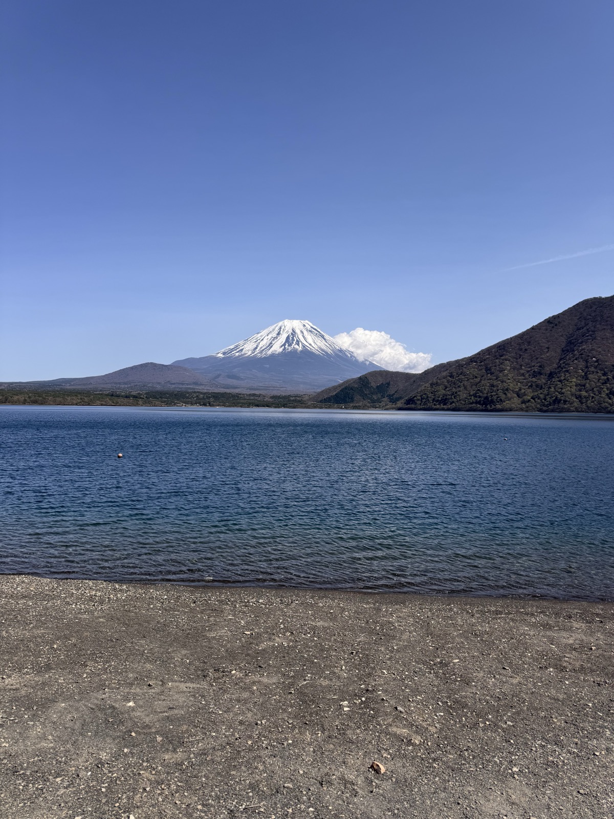 Snow-capped Mount Fuji rising beyond the still water of Lake Motosu